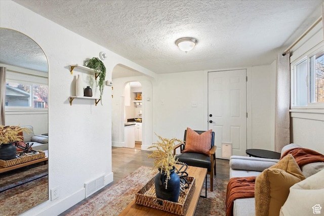 555 15th St, Ogden, UT 84404 - living room featuring arched walkways, a textured ceiling, baseboards, wood finished floors, and visible vents
