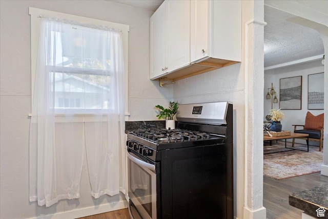 555 15th St, Ogden, UT 84404 - kitchen with wood finished floors, stainless steel gas stove, dark countertops, a textured ceiling, and white cabinets
