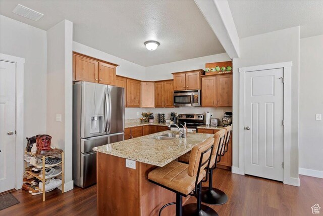 1545 N 420 W Unit 103, Logan, UT 84341 - kitchen with dark wood-style flooring, light stone countertops, appliances with stainless steel finishes, an island with sink, and visible vents