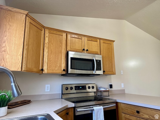 819 E 725 N, Ogden, UT 84404 - kitchen featuring brown cabinets, appliances with stainless steel finishes, a sink, light countertops, and lofted ceiling