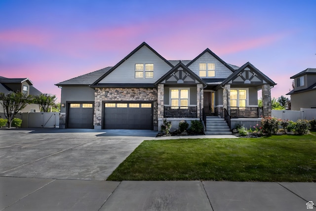 craftsman house with covered porch, driveway, a front yard, a gate, and stone siding
