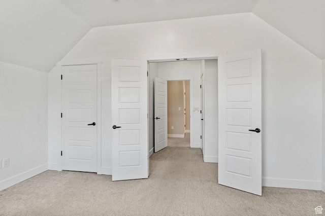 additional living space featuring light colored carpet, baseboards, and lofted ceiling