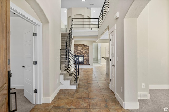 foyer with baseboards, a high ceiling, stairs, and visible vents