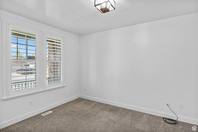 empty room featuring baseboards, carpet flooring, and visible vents