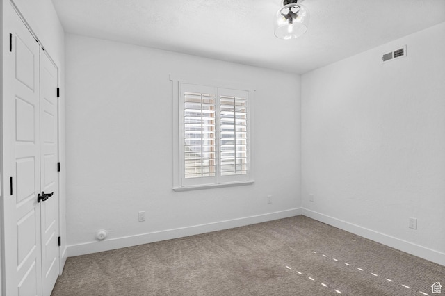 empty room featuring visible vents, carpet, and baseboards