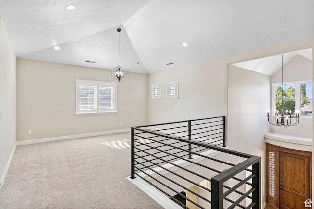 interior space with vaulted ceiling, a healthy amount of sunlight, an upstairs landing, and a notable chandelier