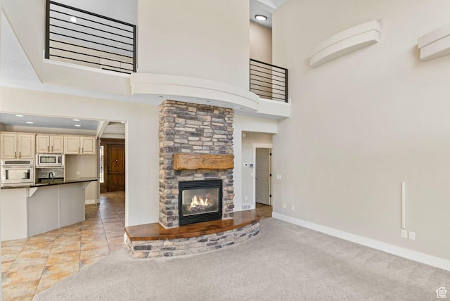 unfurnished living room featuring a high ceiling, a sink, a fireplace, recessed lighting, and baseboards