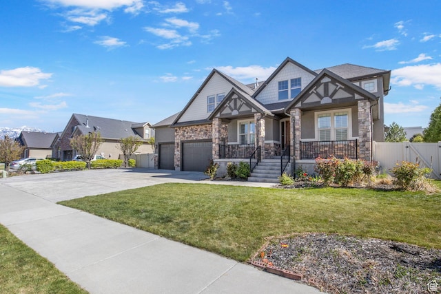 craftsman-style home featuring covered porch, driveway, stone siding, and a front lawn