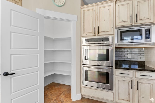 kitchen with dark stone counters, appliances with stainless steel finishes, backsplash, and light brown cabinetry