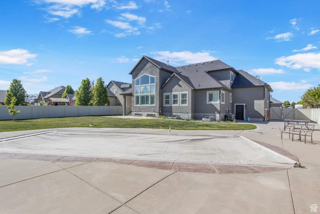 rear view of property featuring a lawn, a gate, stucco siding, and fence