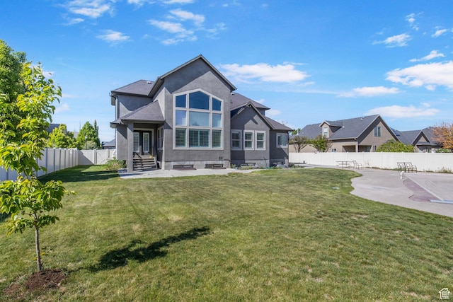 rear view of house with a yard, a patio, a fenced backyard, and stucco siding