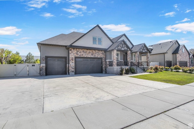view of front of house featuring stone siding, a garage, a front yard, a gate, and concrete driveway