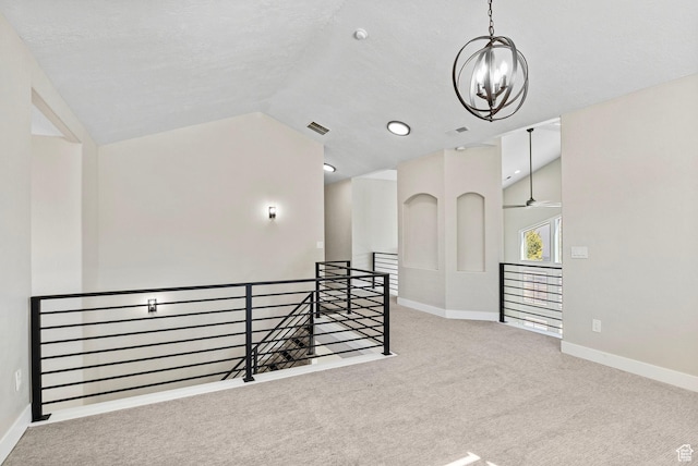 carpeted empty room featuring an inviting chandelier, baseboards, vaulted ceiling, and visible vents