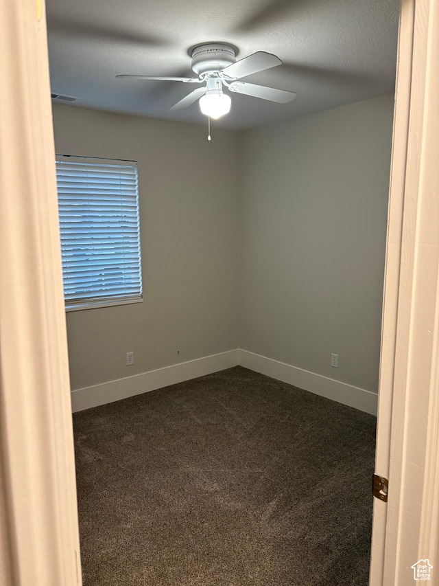 unfurnished room featuring dark colored carpet, baseboards, ceiling fan, and visible vents