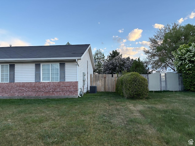 view of home's exterior with fence, a lawn, and brick siding