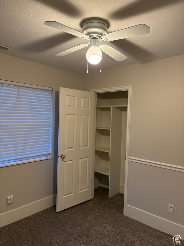 unfurnished bedroom featuring dark carpet, a ceiling fan, baseboards, and visible vents