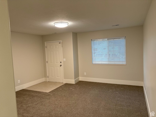 carpeted foyer with a textured ceiling and baseboards