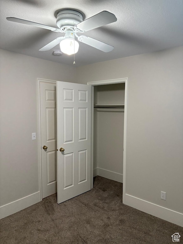 unfurnished bedroom featuring a ceiling fan, baseboards, dark carpet, and a closet