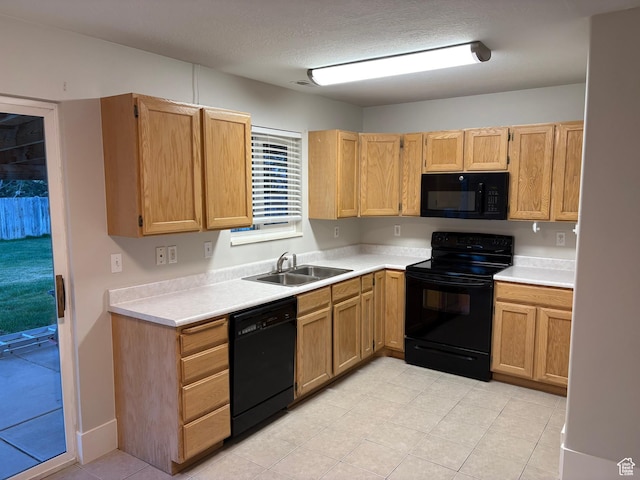 kitchen featuring a sink, light countertops, light tile patterned floors, and black appliances