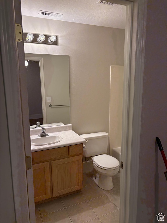 full bath with visible vents, tile patterned flooring, vanity, toilet, and a tub to relax in