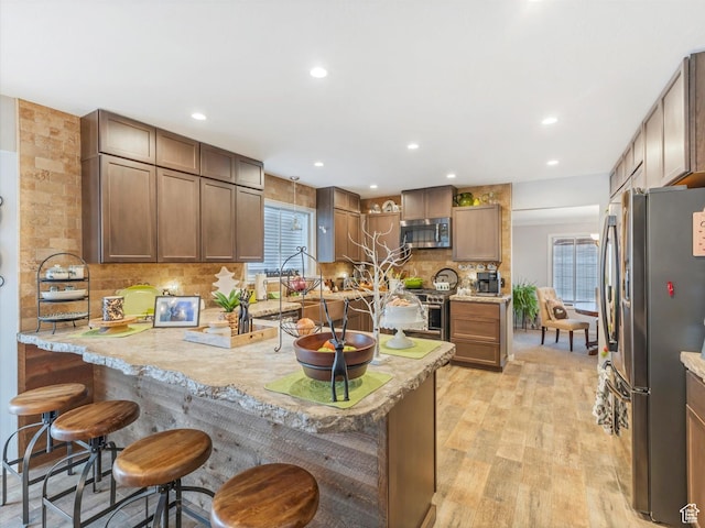 6439 S 1940 E, Murray, UT 84121 - kitchen with decorative backsplash, a peninsula, light wood-style floors, a kitchen bar, and stainless steel appliances