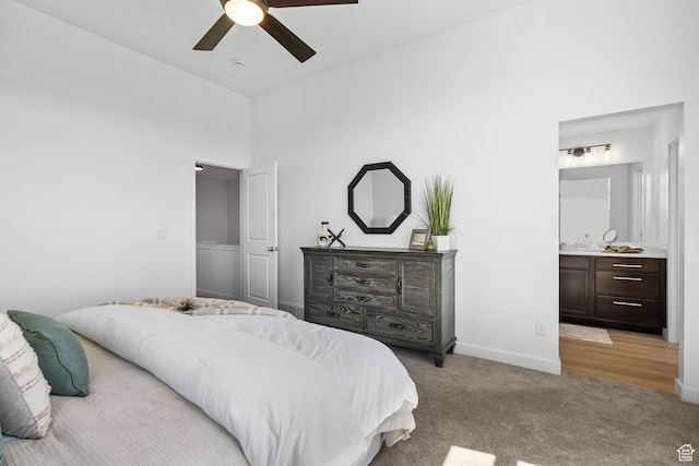 bedroom with ceiling fan, wet bar, light colored carpet, baseboards, and ensuite bath