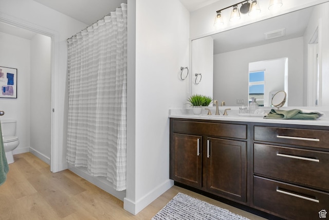 bathroom featuring visible vents, wood finished floors, toilet, and vanity