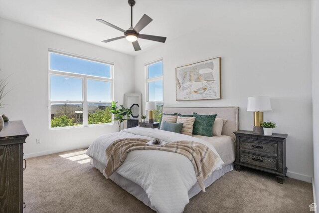 bedroom with a ceiling fan, baseboards, and light colored carpet