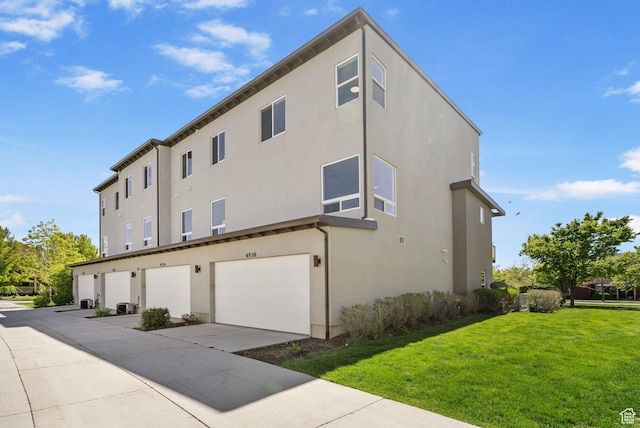 exterior space with an attached garage, stucco siding, and a yard