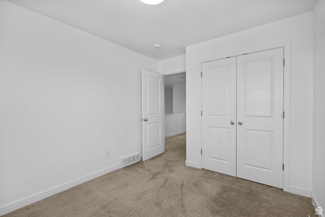 unfurnished bedroom featuring baseboards, carpet, visible vents, and a closet