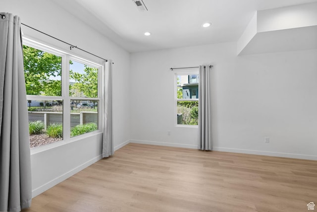 empty room featuring light wood-style floors, baseboards, recessed lighting, and visible vents
