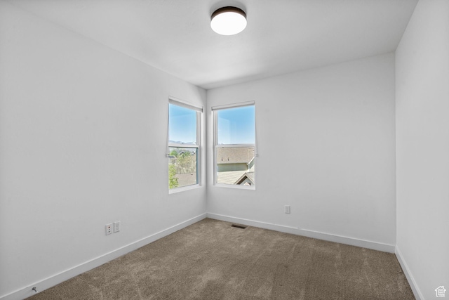 spare room featuring baseboards, carpet flooring, and visible vents