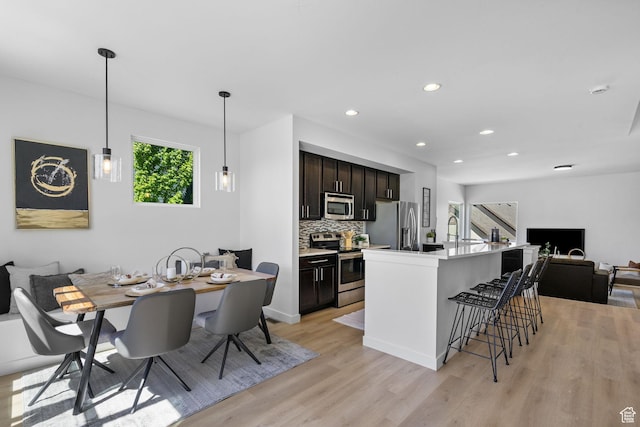 kitchen with stainless steel appliances, open floor plan, a healthy amount of sunlight, and light wood finished floors