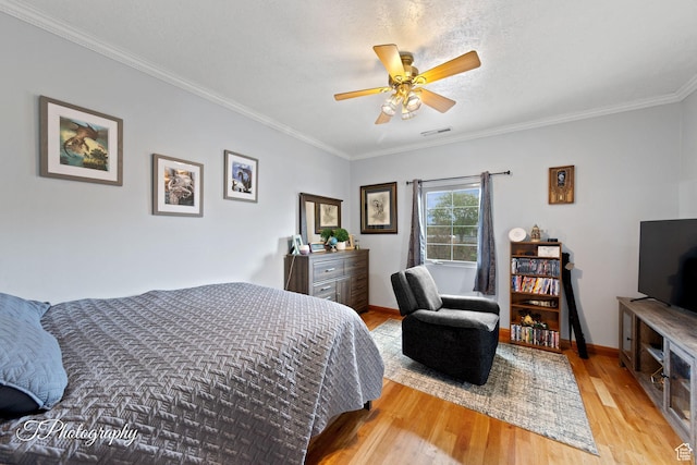 bedroom featuring ceiling fan, light wood finished floors, baseboards, visible vents, and ornamental molding