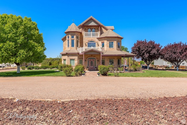 victorian house featuring a tile roof, a front yard, covered porch, and stone siding