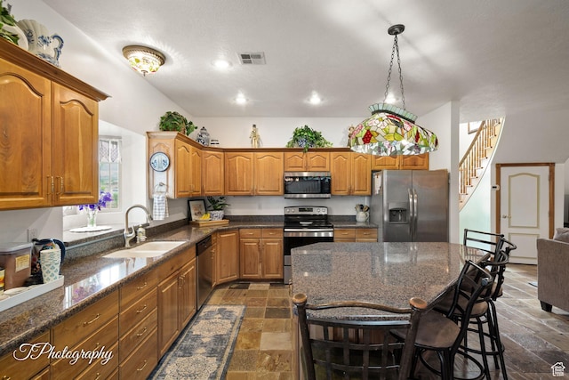 kitchen featuring a sink, brown cabinetry, stainless steel appliances, visible vents, and stone tile flooring