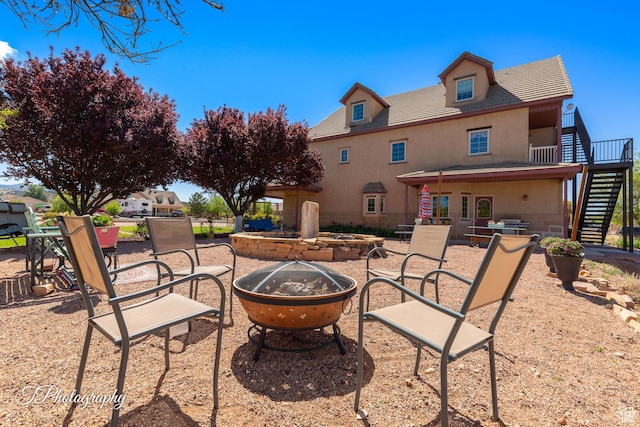 back of property with stucco siding, a patio, stairs, and an outdoor fire pit