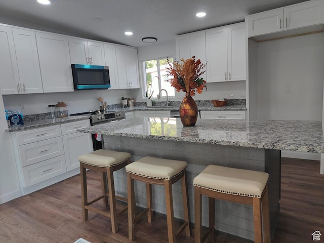 3112 S 3780 W, West Valley City, UT 84120 - kitchen with stainless steel appliances, dark wood-type flooring, recessed lighting, white cabinets, and a kitchen breakfast bar
