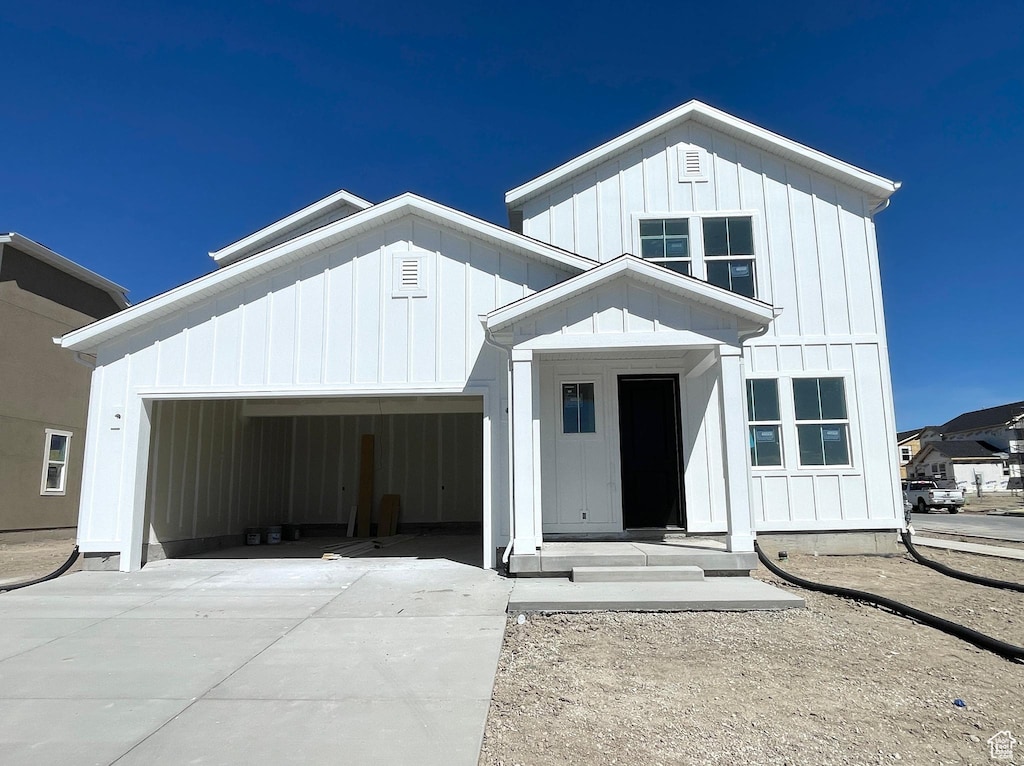 modern farmhouse featuring board and batten siding, an attached garage, and driveway
