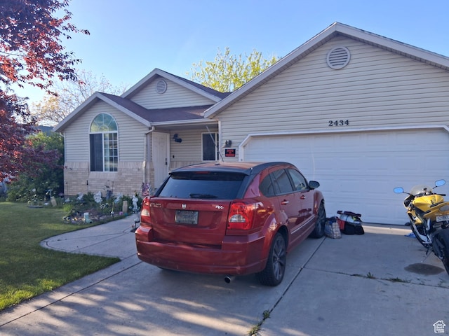 single story home with brick siding, a front lawn, an attached garage, and concrete driveway