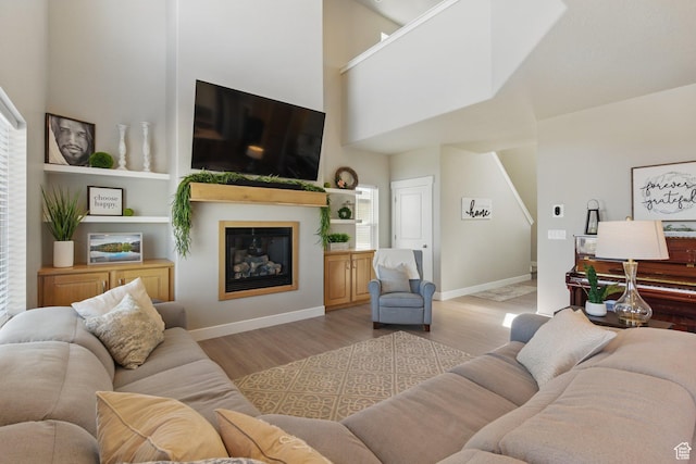1147 N Carriage Ln, Spanish Fork, UT 84660 - living room with a glass covered fireplace, baseboards, light wood-type flooring, and a towering ceiling