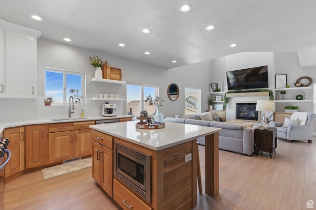 1147 N Carriage Ln, Spanish Fork, UT 84660 - kitchen featuring a glass covered fireplace, a center island, light countertops, stainless steel microwave, and a sink