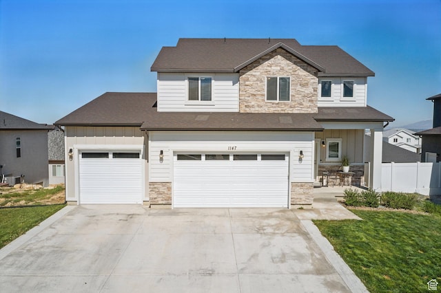 view of front of house with an attached garage, central AC, stone siding, board and batten siding, and concrete driveway