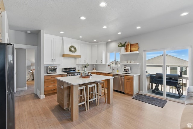 1147 N Carriage Ln, Spanish Fork, UT 84660 - kitchen with appliances with stainless steel finishes, a sink, a breakfast bar area, light countertops, and light wood-style flooring