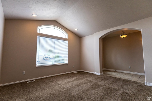 4902 W Pine Laurel Ln, West Jordan, UT 84081 - tiled spare room with carpet floors, visible vents, lofted ceiling, a textured ceiling, and arched walkways