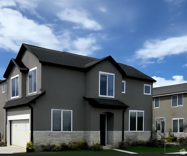 view of front facade with an attached garage, stucco siding, a front yard, and stone siding