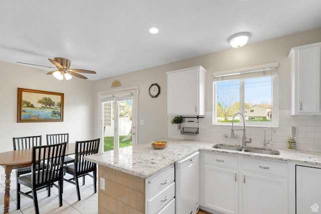 kitchen with a sink, dishwasher, a peninsula, a ceiling fan, and tasteful backsplash