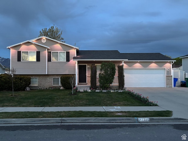 tri-level home with an attached garage, driveway, and a front yard