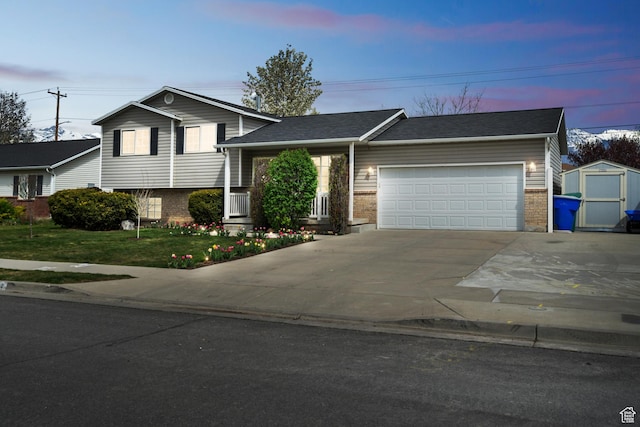 tri-level home with brick siding, a garage, driveway, and a storage unit