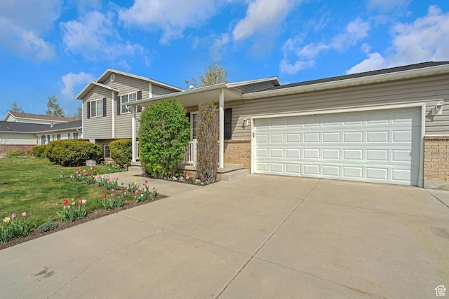 split level home with a garage, a front yard, driveway, and brick siding